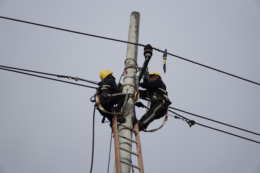 a couple of men standing on top of power lines