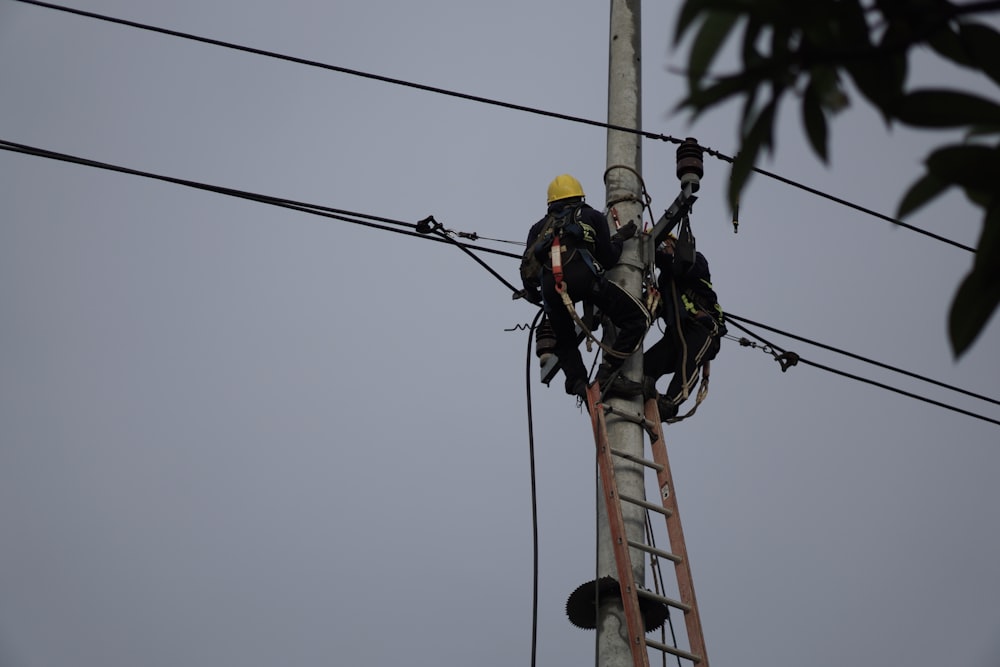 a couple of men standing on top of a power line