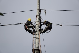 a couple of men standing on top of power lines