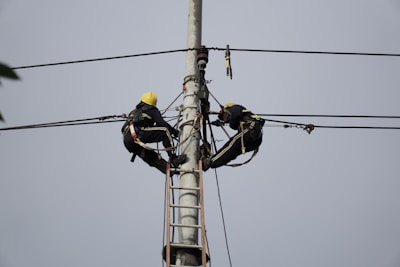 a couple of men standing on top of power lines