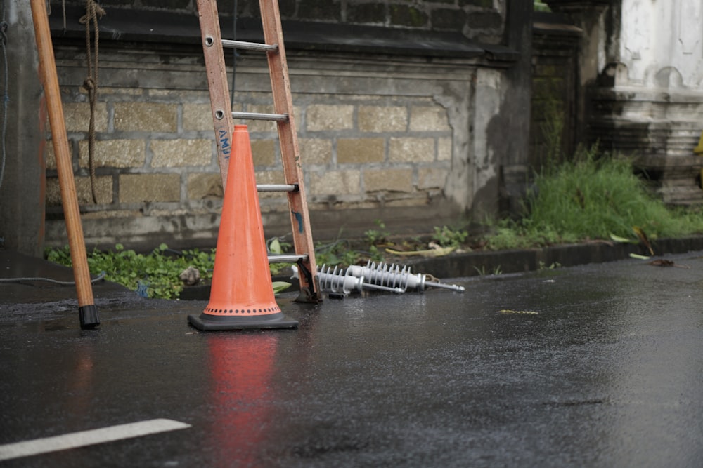 an orange traffic cone sitting on the ground next to a ladder