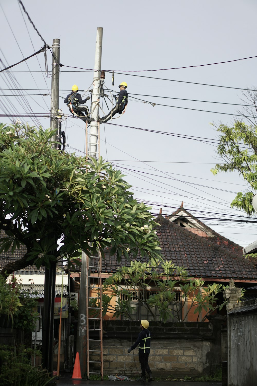 a man in a yellow safety vest working on a power line