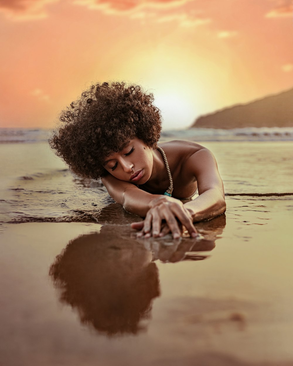 a woman laying on top of a sandy beach next to the ocean