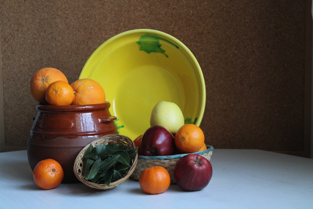 a bowl of oranges, apples, and other fruit on a table