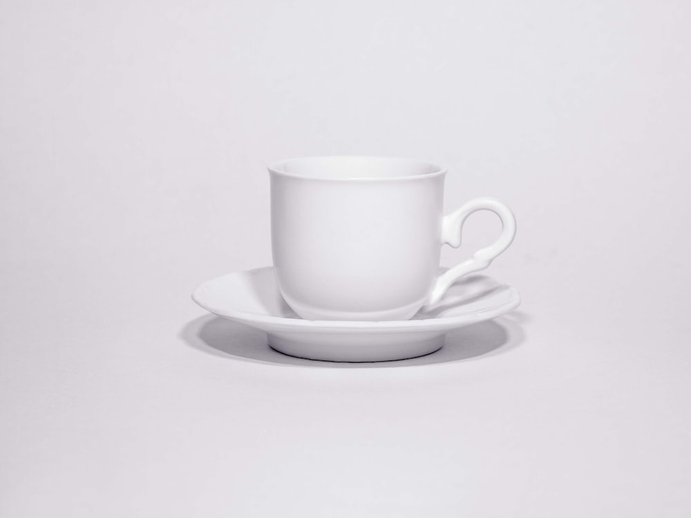 a white cup and saucer on a white table