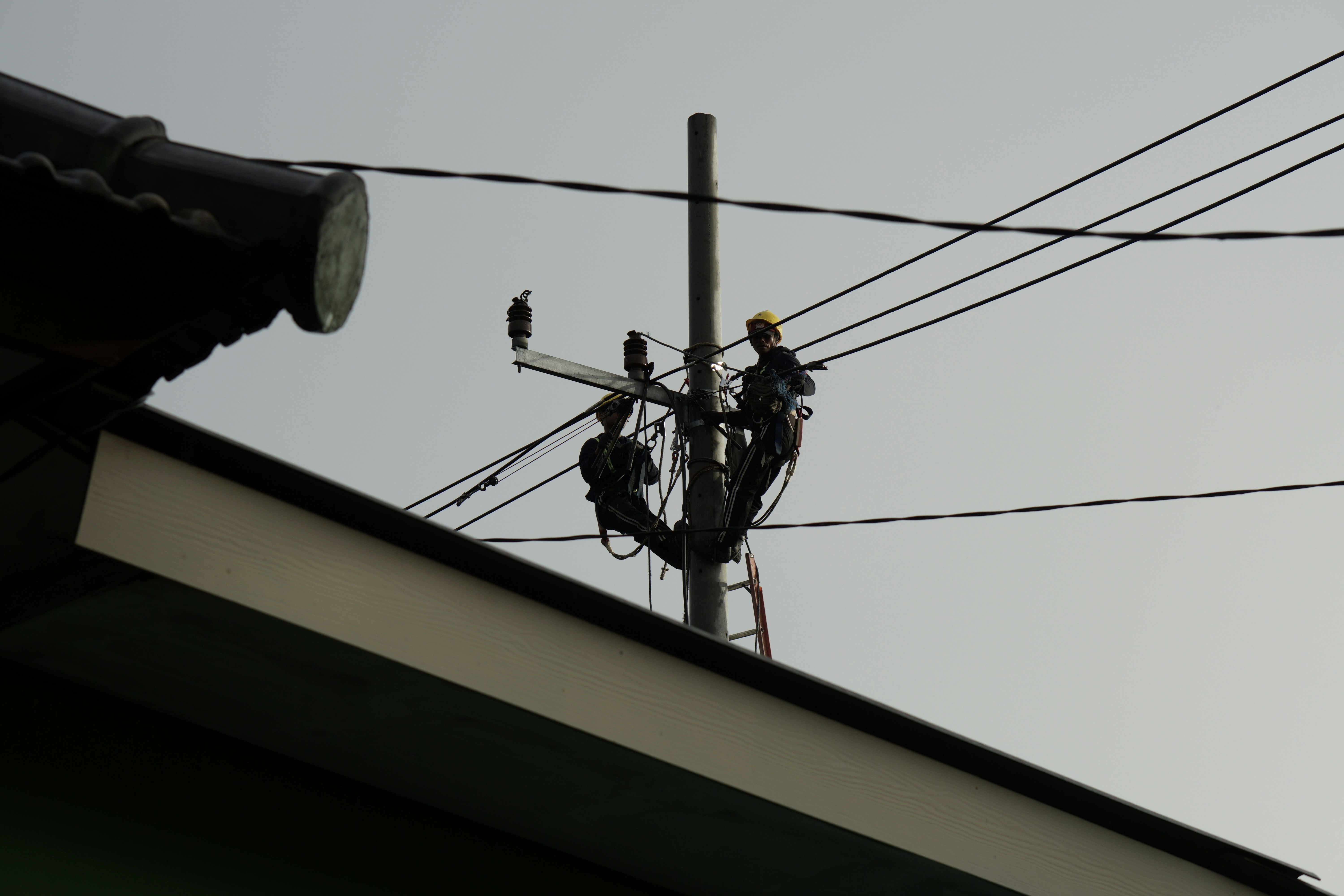 a power line with a man on a ladder working on it