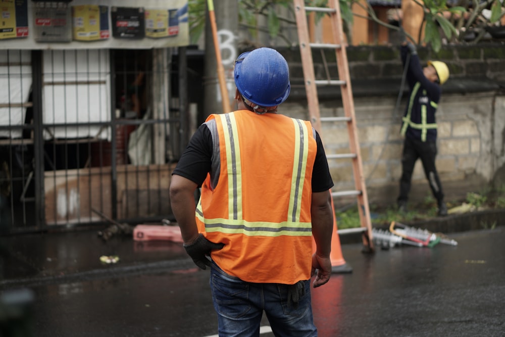 a man in an orange safety vest and a ladder