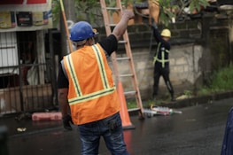 a man in an orange safety vest and a ladder