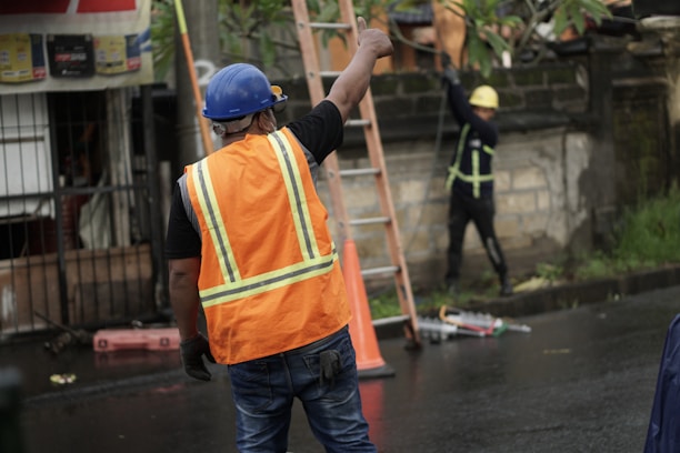 a man in an orange safety vest and a ladder