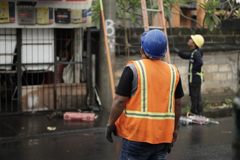 a man in an orange vest and a man in a blue helmet