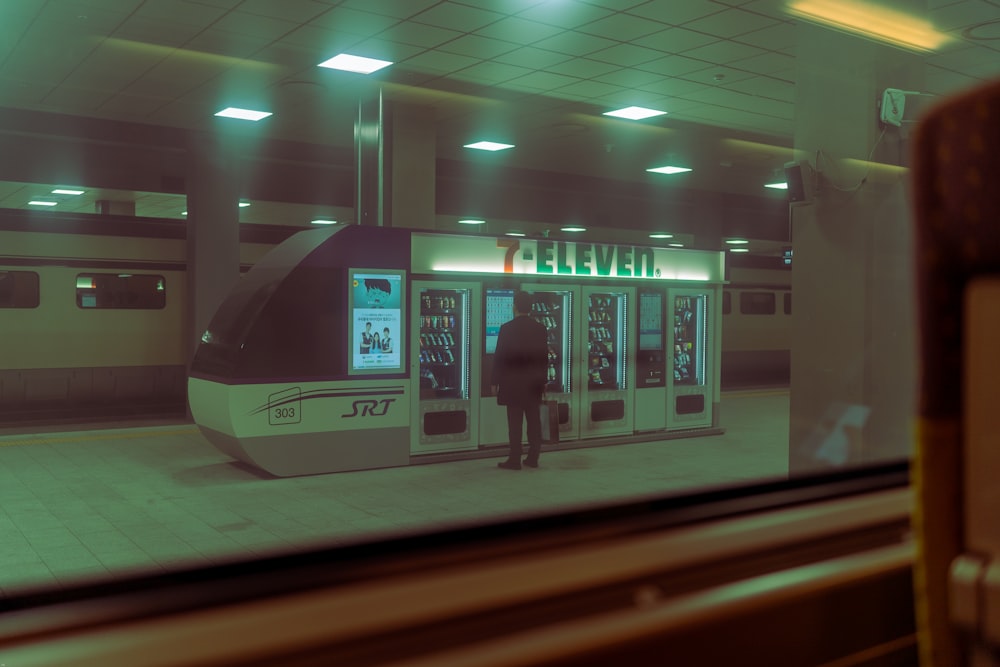 a man standing in front of a machine in a train station