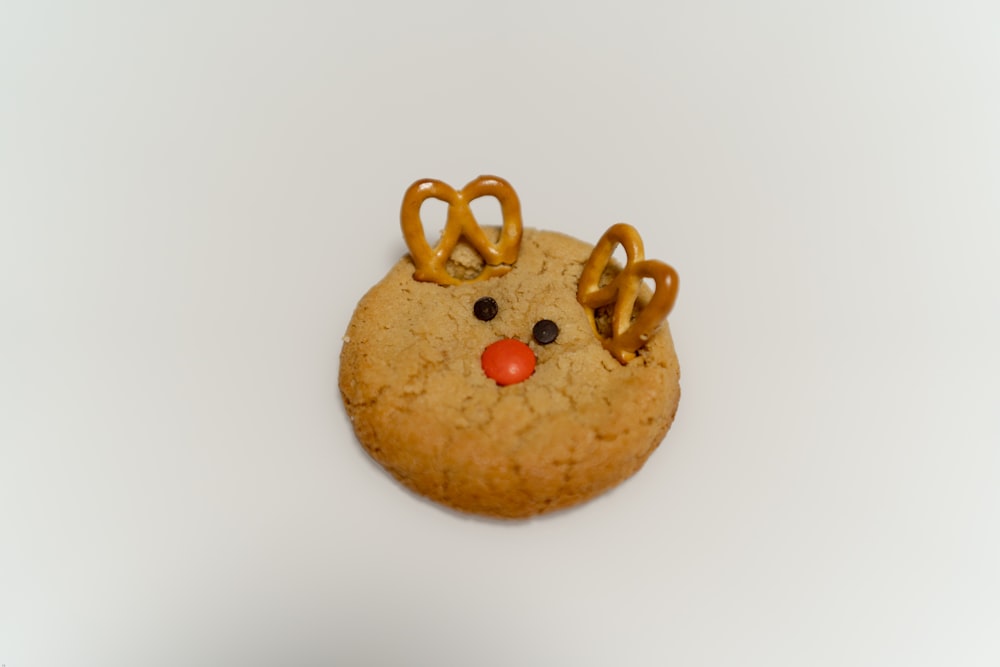 a cookie shaped like a reindeer's head with pretzels on its nose