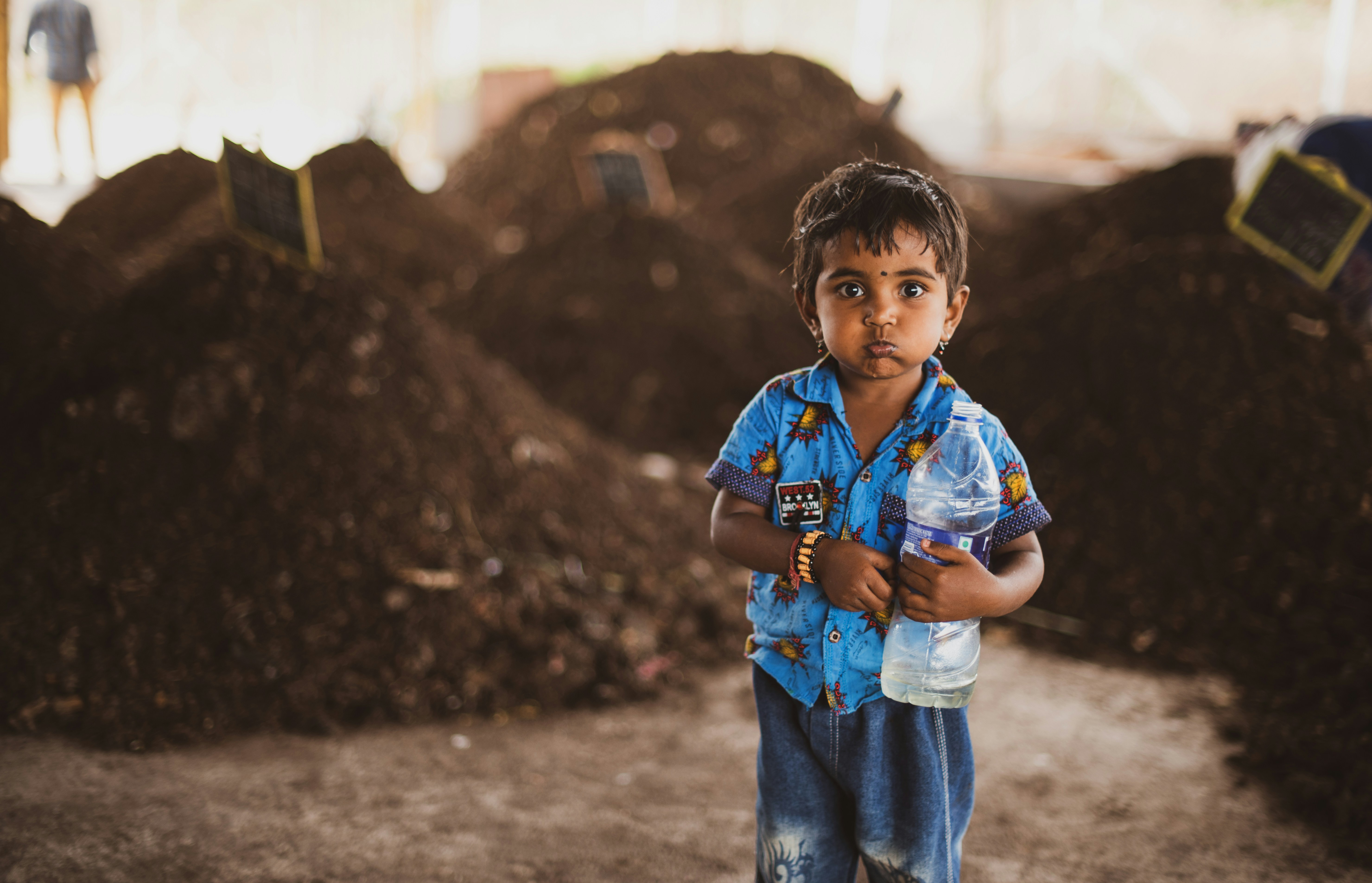 a young boy standing in front of a pile of dirt
