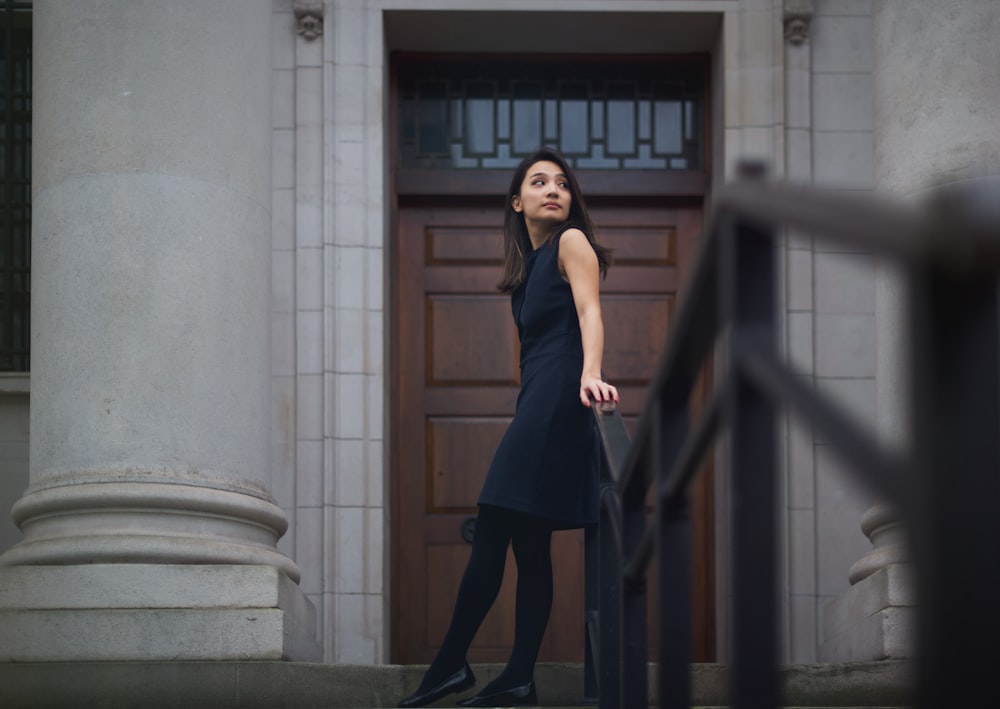 a woman in a black dress is standing in front of a door