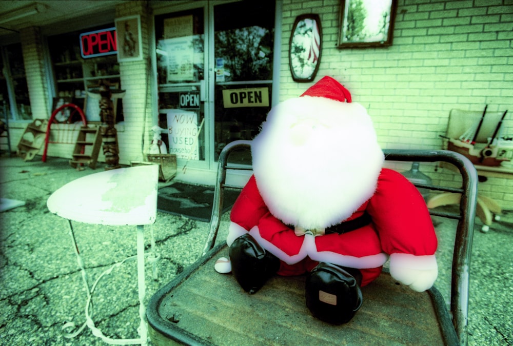 a santa clause sitting on a chair outside of a store