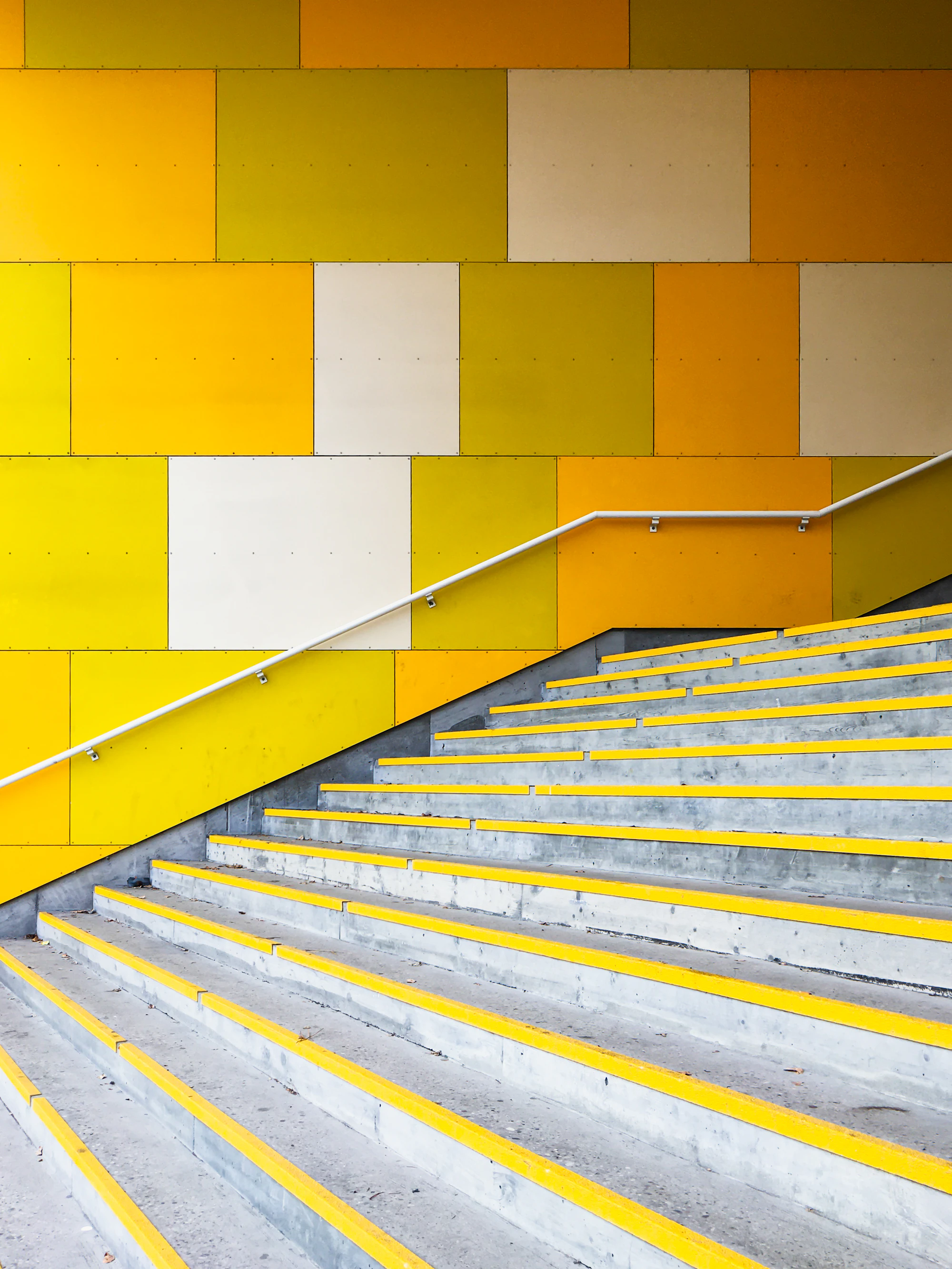 Steps with a yellow handrail against a yellow wall