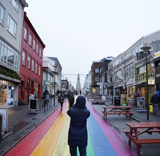 a person walking down a street with a rainbow painted on it