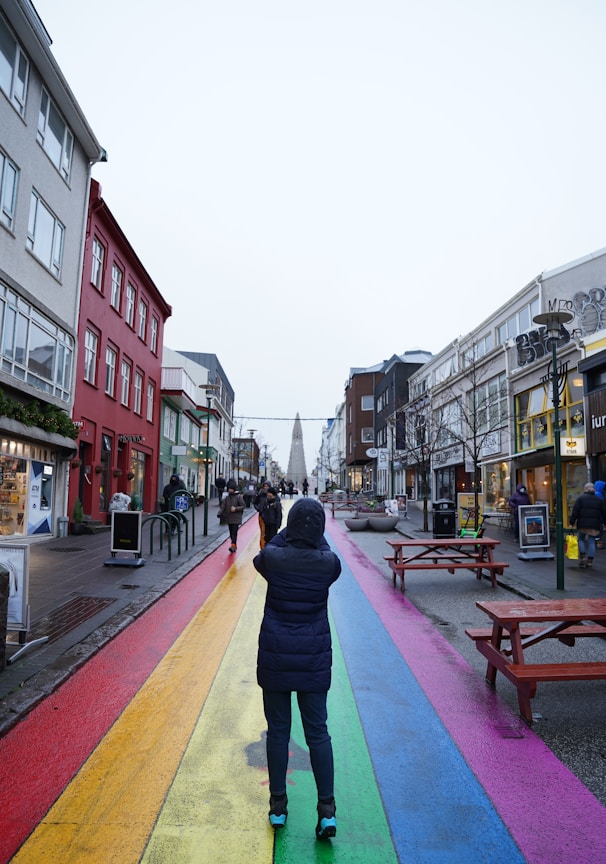 a person walking down a street with a rainbow painted on it