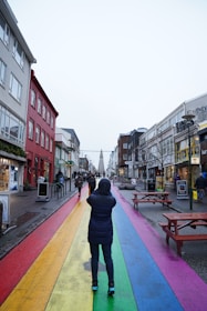 a person walking down a street with a rainbow painted on it
