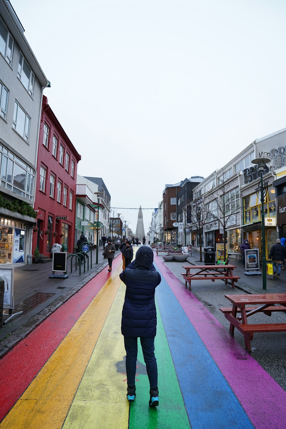 Eine Person, die eine Straße entlang geht, auf die ein Regenbogen gemalt ist