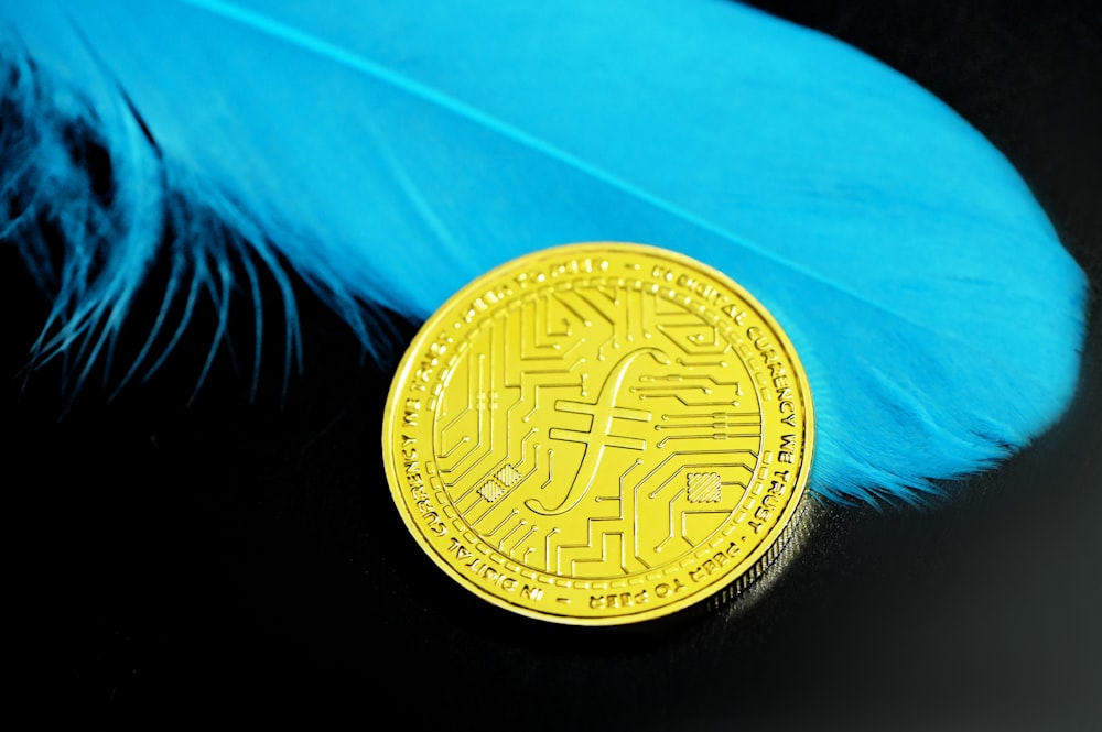 a bit coin sitting on top of a blue feather