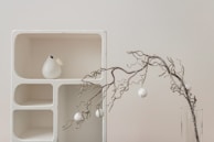 A stylish home decor piece featuring delicate white gold accents, placed on a minimalist white shelf.