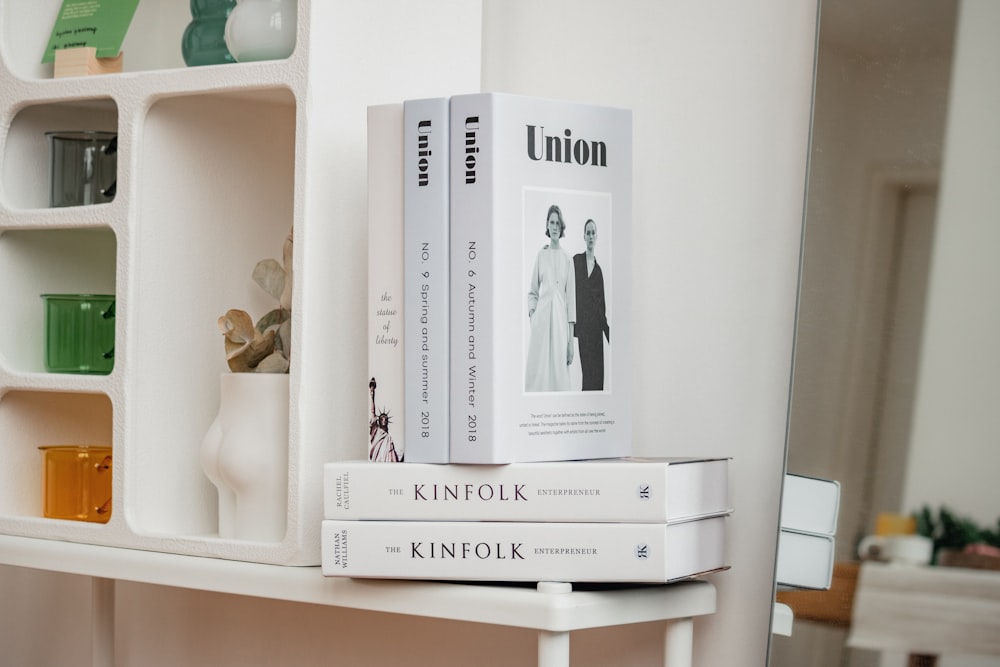 a couple of books sitting on top of a white shelf