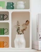 A minimalist shelf displaying curated ceramics and delicate plants.