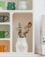 Close-up of a delicate pastel-colored 3D printed vase on a minimalist wooden shelf.