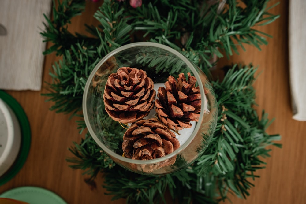 three pine cones in a glass bowl on a table