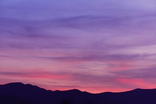 A serene landscape photograph showcasing a sunset over mountains.