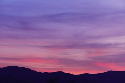 A serene landscape photograph capturing a sunset over mountains.