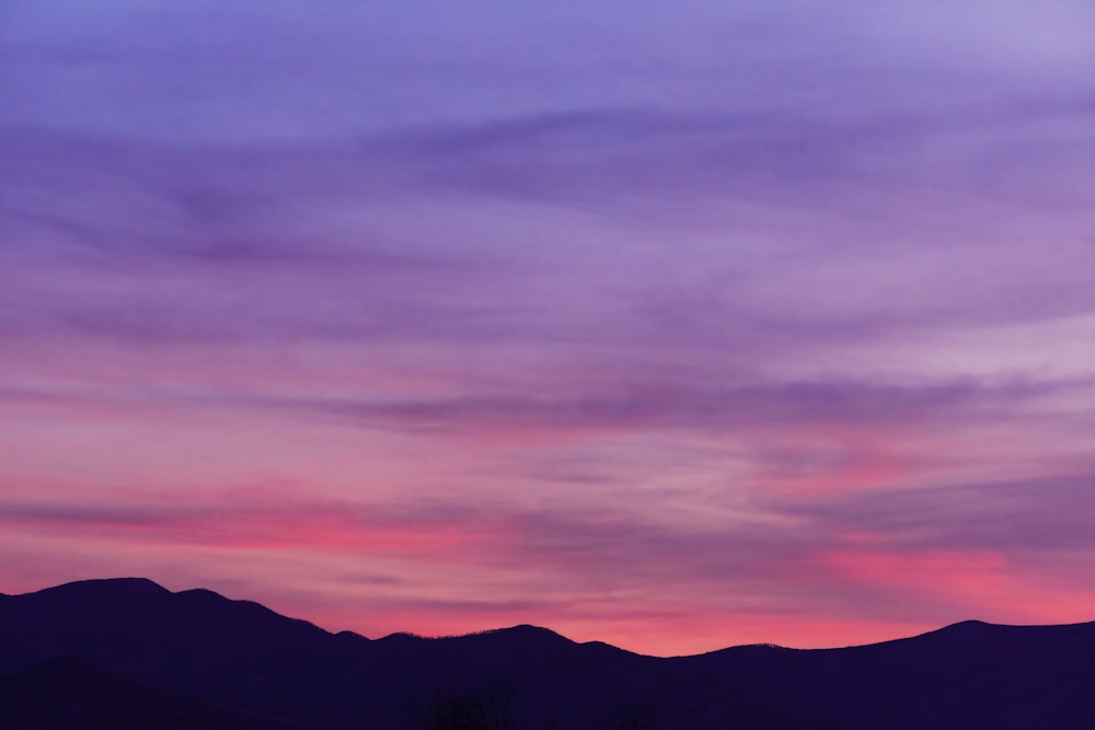 a purple and blue sky with mountains in the background