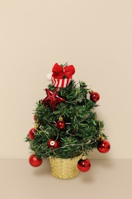 a small christmas tree with ornaments in a basket