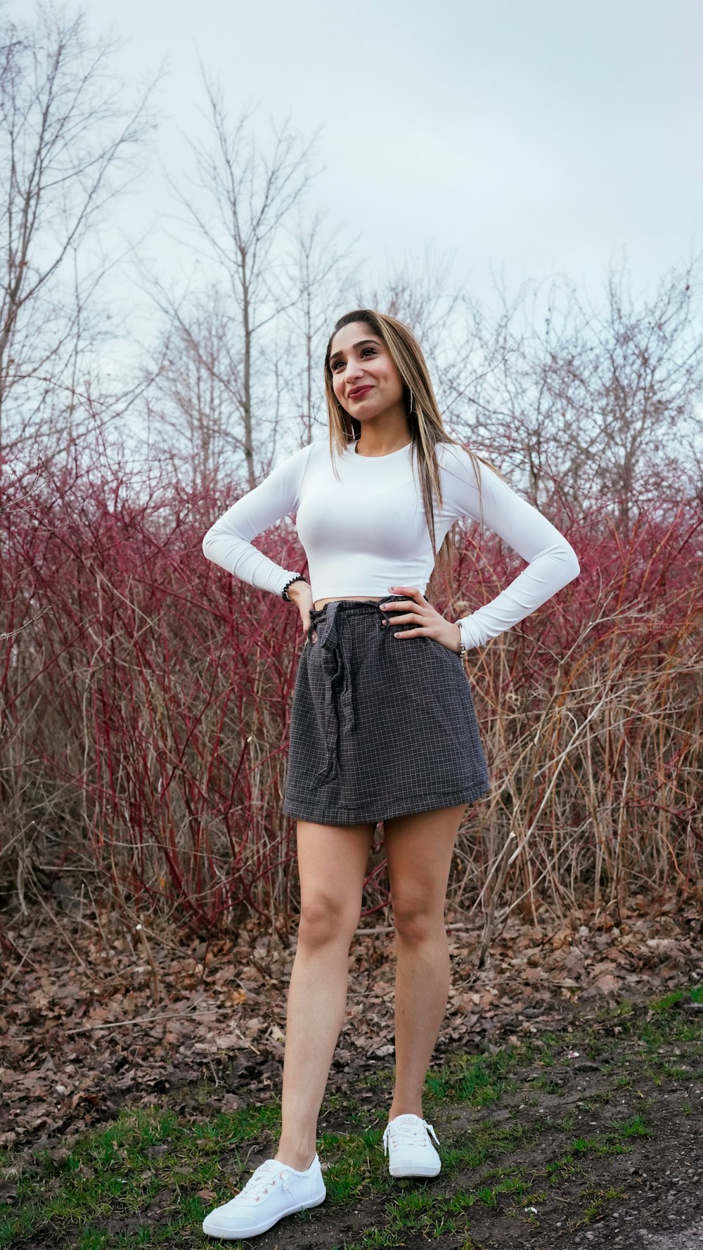 a woman standing in front of some bushes