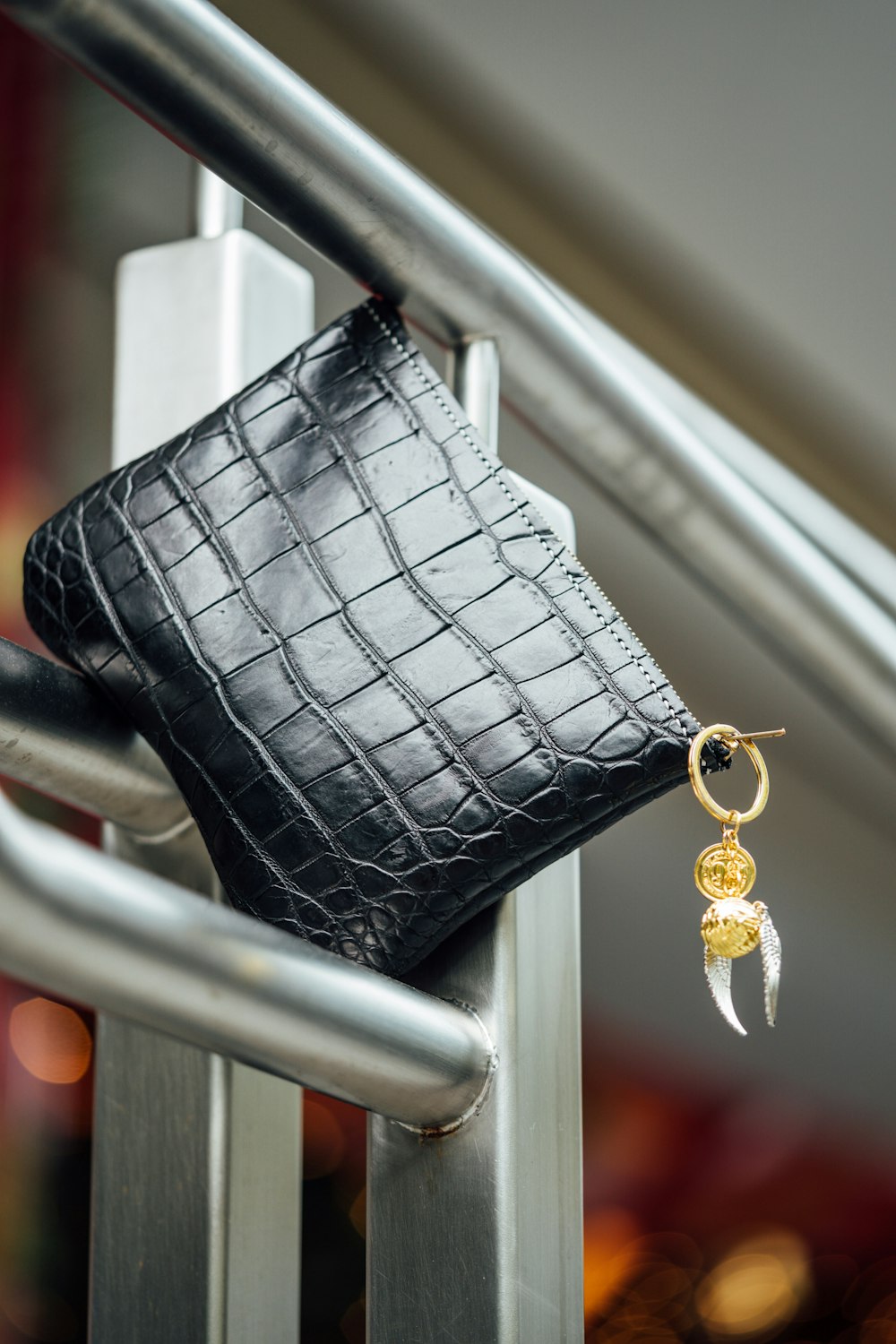 a black purse hanging on a metal hand rail