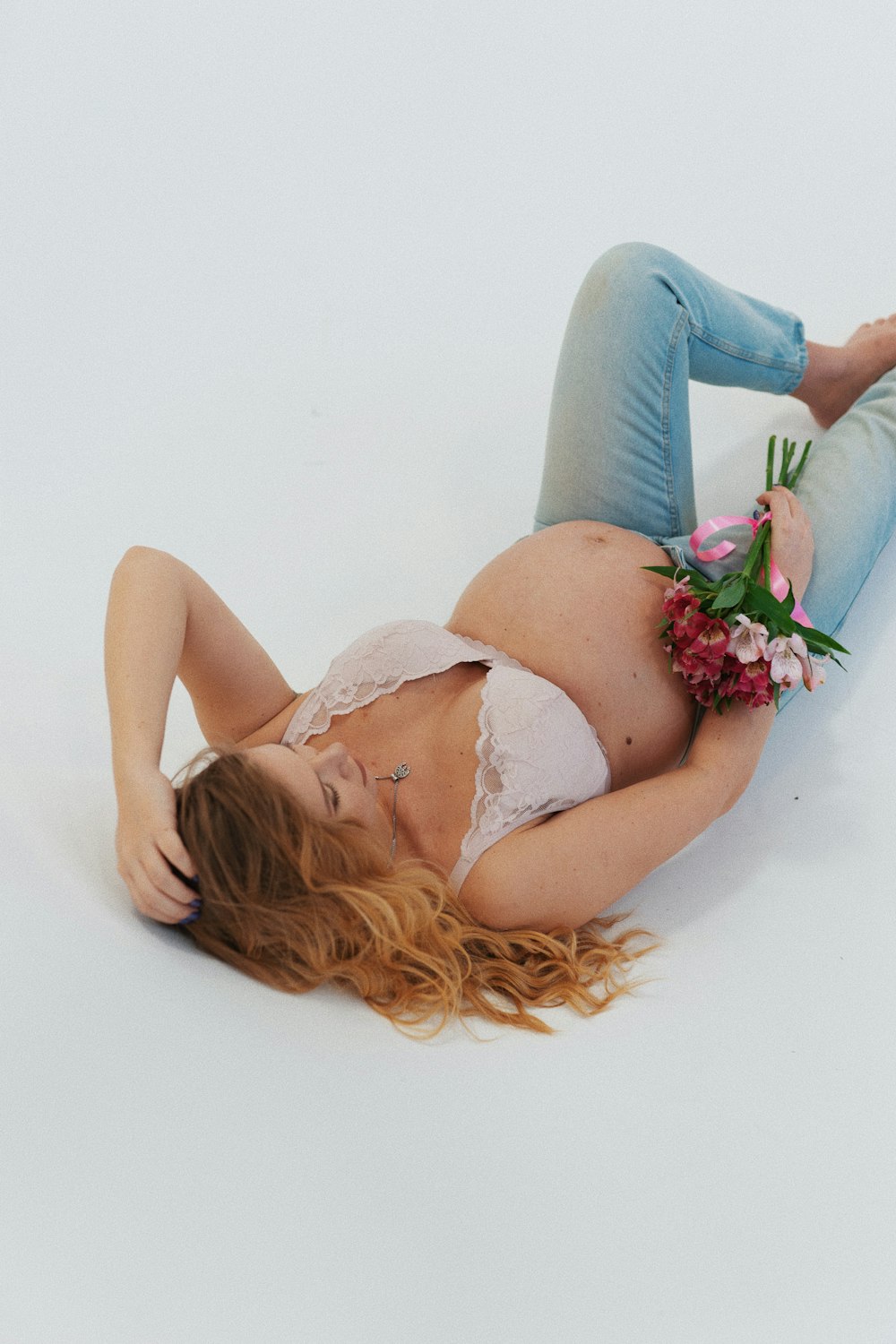 a pregnant woman laying on the ground with flowers in her hair