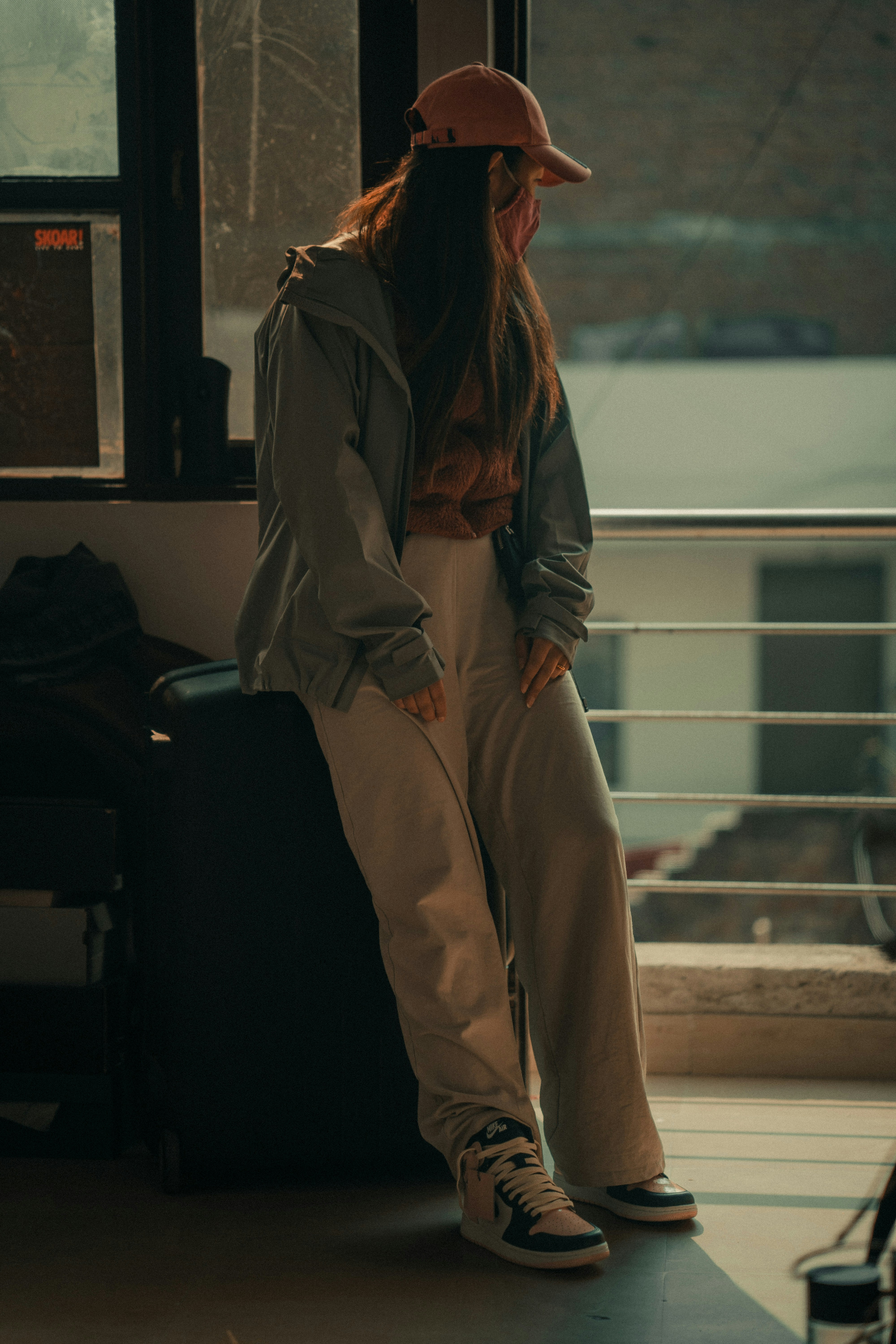 a woman sitting on top of a suitcase next to a window