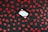A black wooden surface is scattered with numerous red heart-shaped cutouts. In the center sits a small white gift box adorned with diagonal red stripes.