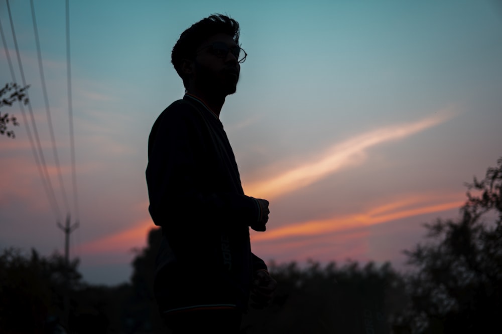 a silhouette of a man standing in front of a sunset