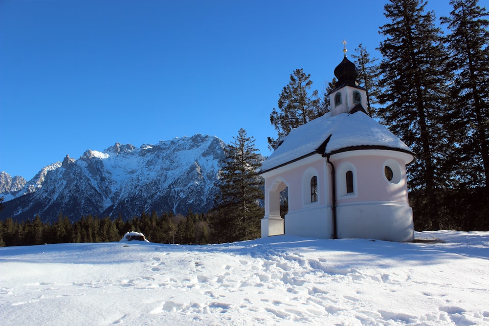 a church in the snow with mountains in the background