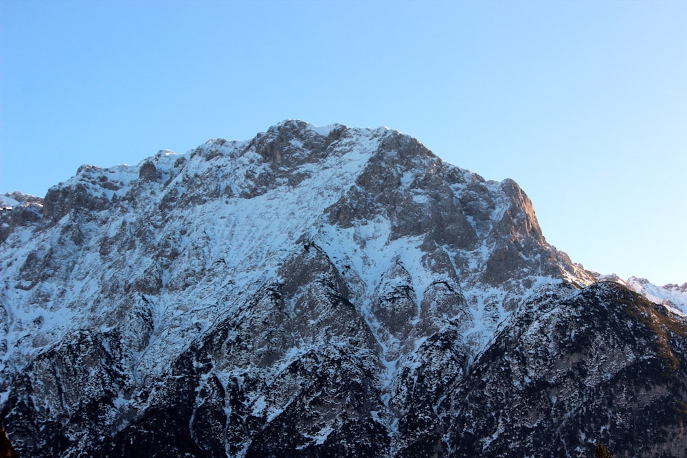 a large mountain covered in snow under a blue sky