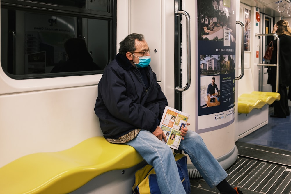 a man wearing a face mask while sitting on a train