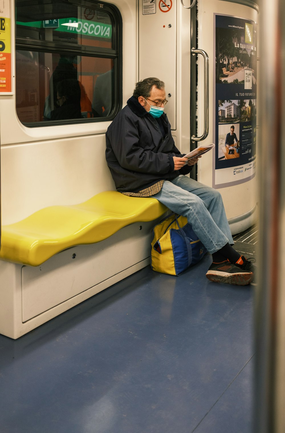 a man sitting on a subway reading a book