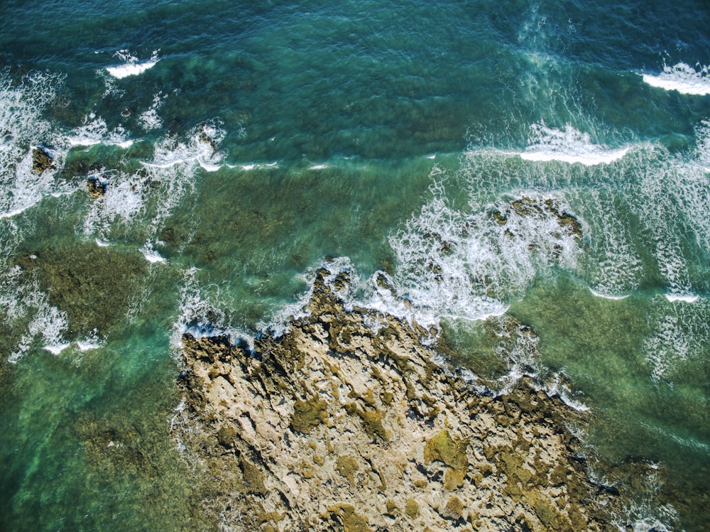 an aerial view of the ocean and rocks