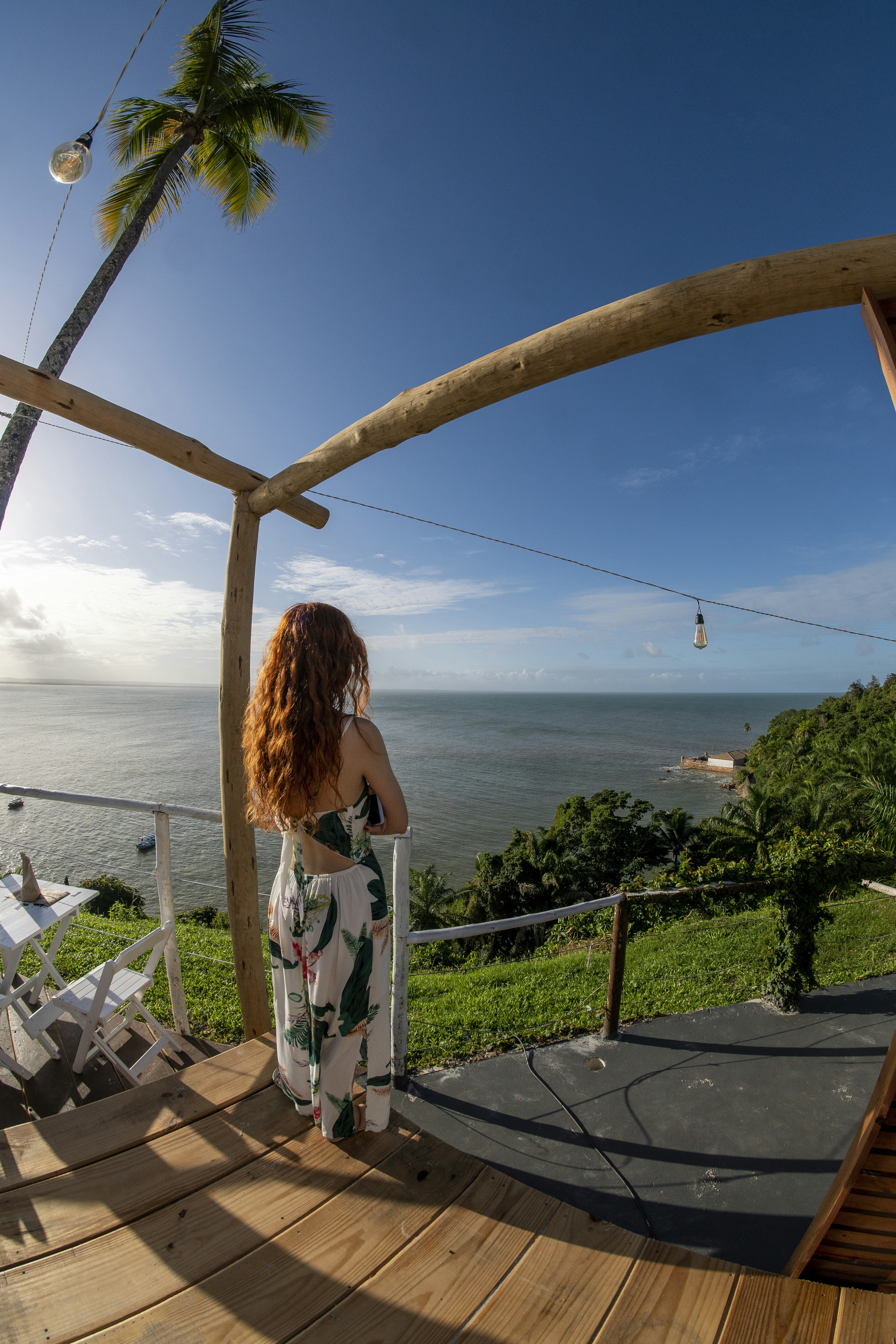 A woman standing on a deck looking out at the ocean photo – Free Ocean ...