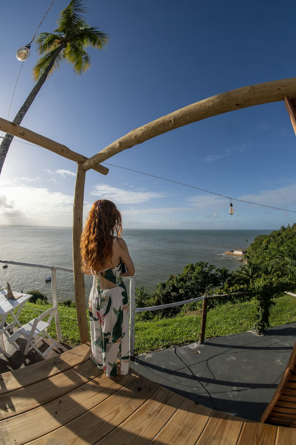 Una mujer parada en una terraza mirando hacia el océano