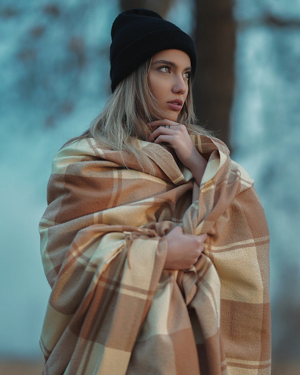 a woman wearing a plaid blanket and a black hat