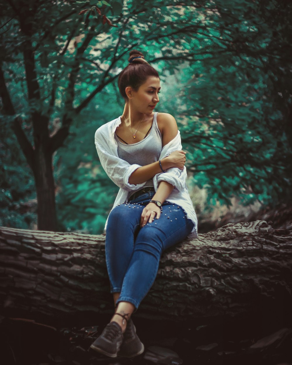 uma mulher sentada em um tronco na floresta