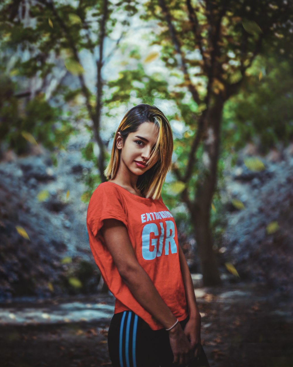 a young woman standing in front of a forest